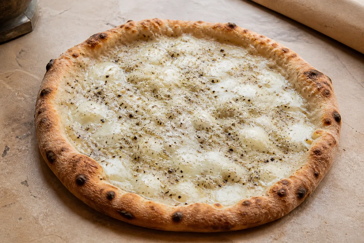 Pizza cacio e pepe maison avec pecorino râpé et poivre noir